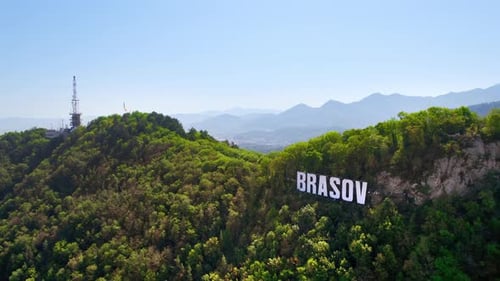 Brasov sign on the top of the hill near the city, green trees, Romania