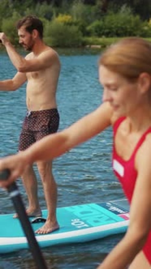 Couple Paddle Boarding on Lake Together in Summer