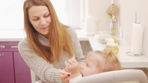 Caring Mother Feeds Baby in Bright Kitchen