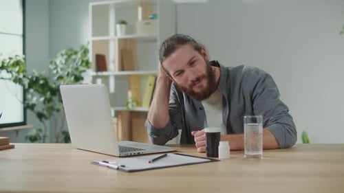 Ill Man at Desk with Laptop and Pills