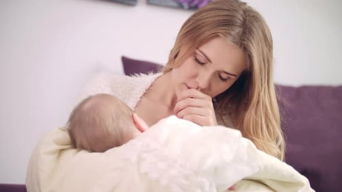 Mother Breastfeeding her Newborn Infant at Home