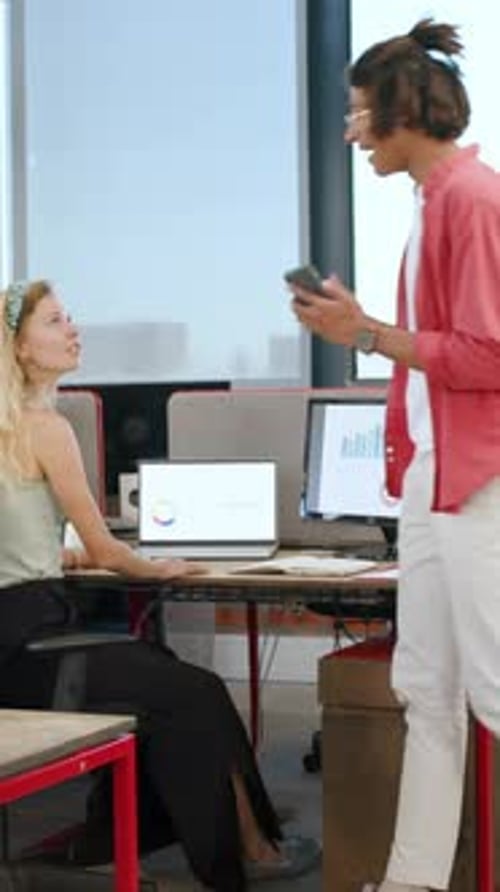 Vertical video: Diverse coworkers ending smartphone call handing documents reviewing graphs at desk