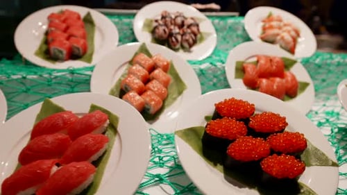 Teller mit einer Vielzahl von Sushi und Brötchen, darunter Nigiri mit Lachs, Sushi mit Kaviar und Maki