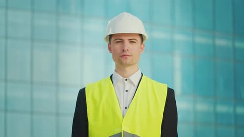 Confident Engineer Smiling with Blueprints by Modern Building