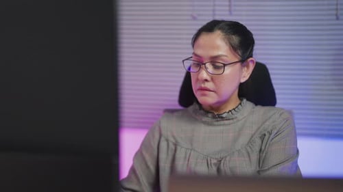 Close-up of young woman wearing glasses looking at large digital glitch screen