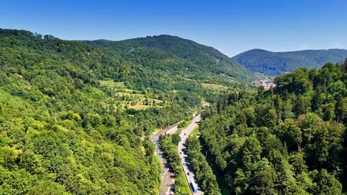 Blick auf die kurvige Bergstraße. Üppige grüne Hügel umgeben eine kurvenreiche Straße an einem klaren, sonnigen Tag