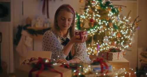 Smiling Woman with Christmas Gifts and Warm Mug
