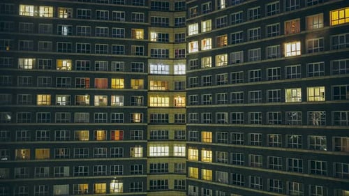 Zeitraffer eines Mehrfamilienhauses mit vielen Fenstern am Abend Ein- und Ausschalten des Lichts in