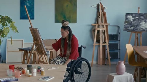Dedicated Young Female Artist with Disability Drawing on Canvas in Cozy Studio