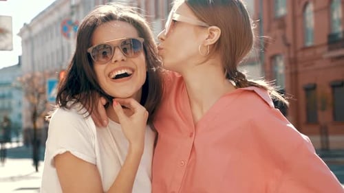 Two young beautiful smiling hipster female outdoors