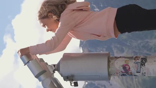 Child Looks Through Telescope at Mountain Views