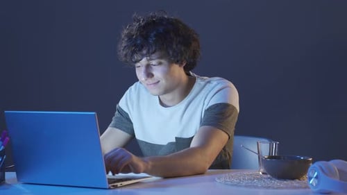Young Adult Typing on Laptop at Night