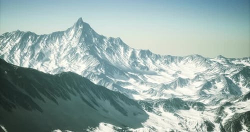 Majestic Snow Capped Mountain Peak with Rugged Terrain Under Clear Sky