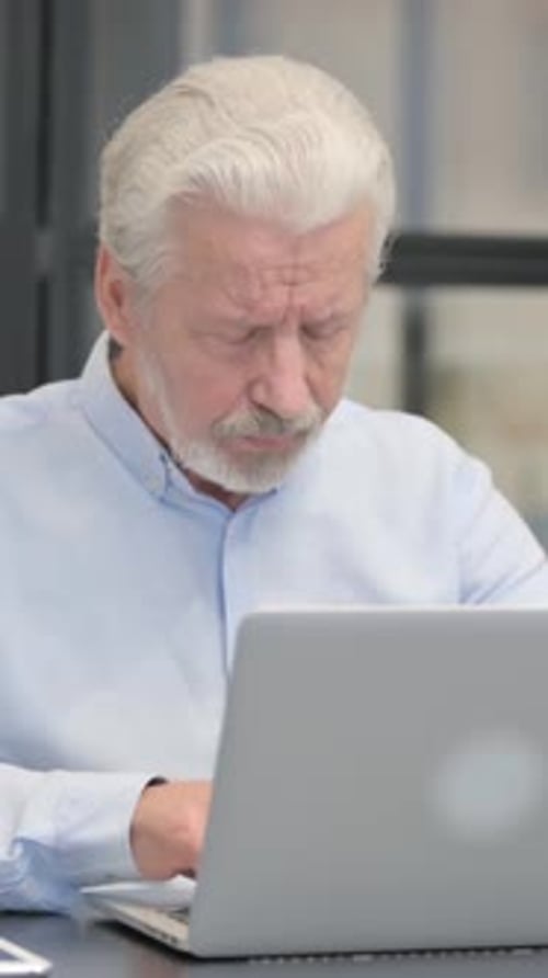 Senior Man with Headache Massaging Temples at Desk