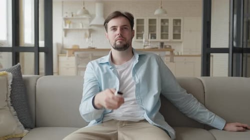 Man Sitting on Couch Using Remote Control