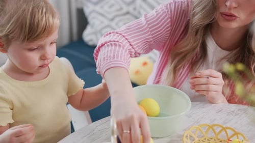 Child and Adult Hands Dye Vibrant Easter Eggs in Bowl
