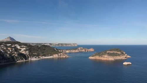 Aerial drone shot of beautiful coastline with turquoise calm sea water and green rocks