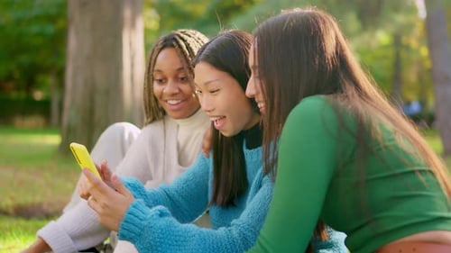 Happy Friends Scrolling the Mobile and Start to Laugh Outdoors