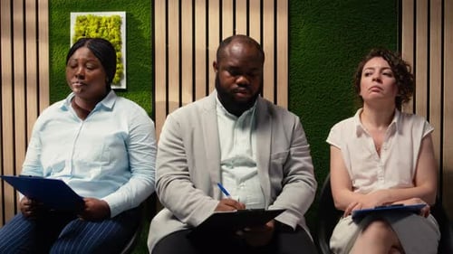 Group of Candidates Waiting in Line in a Corporate Hallway with Their Resumes