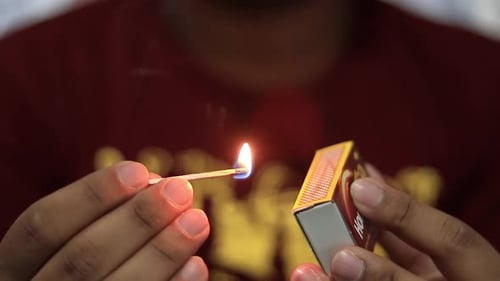 Hands Lighting a Match with Bright Flame