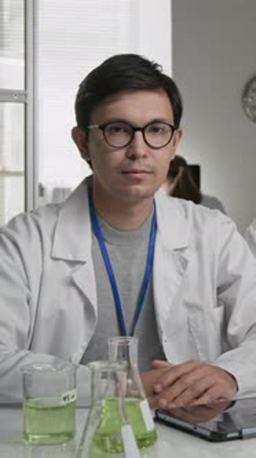 Scientist in Lab Coat at Desk Smiling at Camera