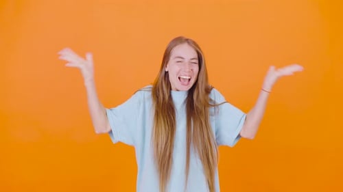 Excited Woman Celebrates Against Orange Background