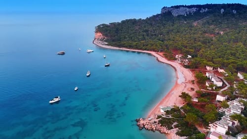 Several yachts stand on the azure clear waterscape near the picturesque shore of Turkey.