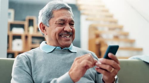 Senior Man Smiling and Using a Phone Indoors