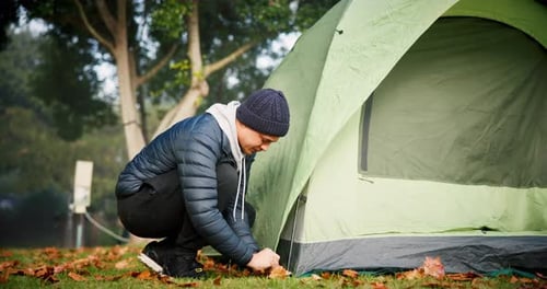 Man, setup and tent at camp in forest for adventure on holiday for relaxing in environment