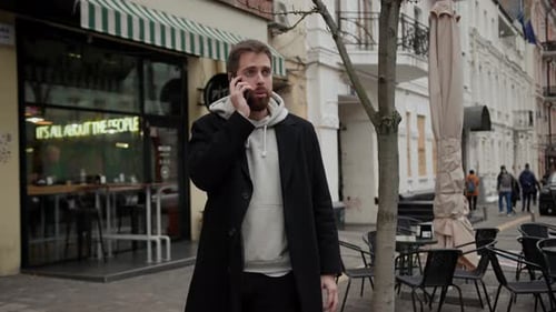 man in a coat talking on the phone in the middle of the city