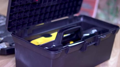 Eine Nahaufnahme des Werkzeugkastens eines Heimwerkers. Handyman erreicht und öffnet die Toolbox und zeigt teilweise Inhalt