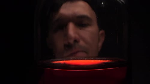 Man Face Viewed Through Red Liquid in Glass