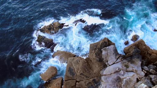 AERIAL: Zoom into ocean waves crashing over rocks at North Bondi, Sydney Australia.