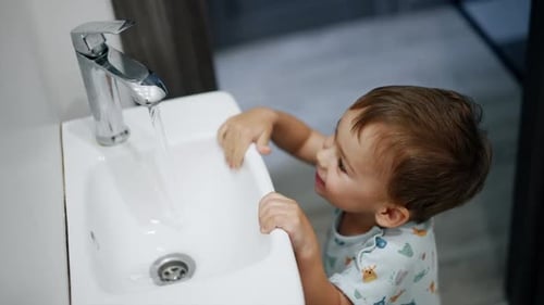 Cute Child Playing with Water in Sink