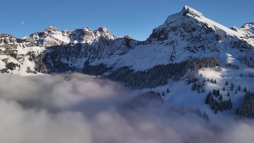 Breathtaking Aerial View of Snowy Alpine Peaks Above Dramatic Clouds