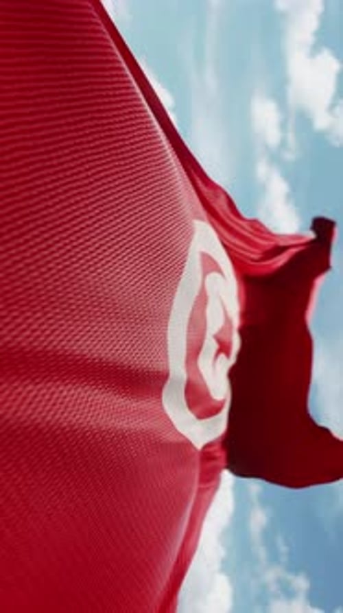 Waving Flag of Tunisia Against Blue Sky