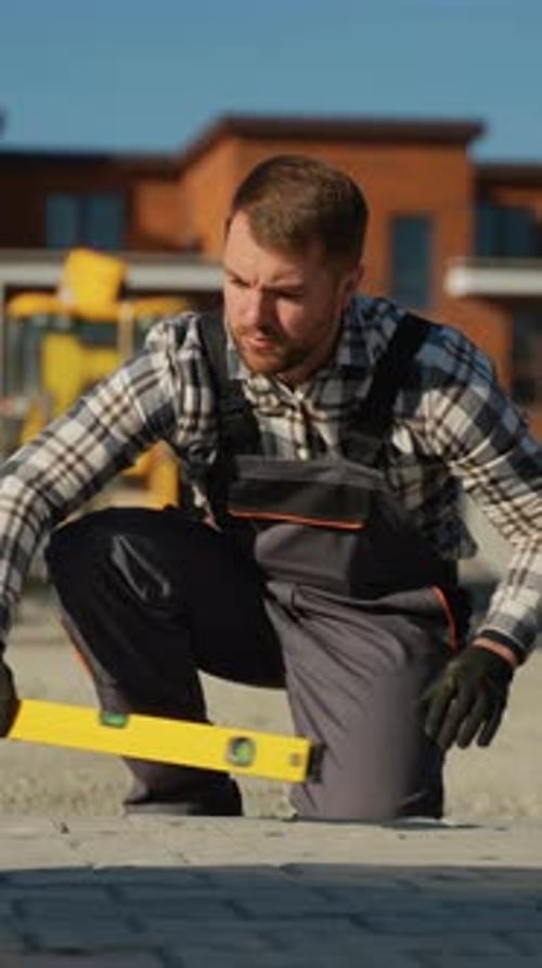 Construction Worker Leveling Stone Pavers on Urban Site
