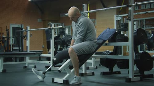 Fit Man with Prosthetic Leg Corrects Prosthesis and Starts to Train in Gym