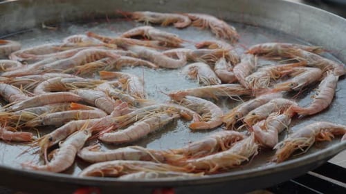 Slow orbiting shot of a large pan of shrimp being cooked to be served