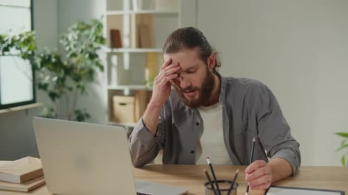 Man Working at Laptop Massaging Temples in Frustration