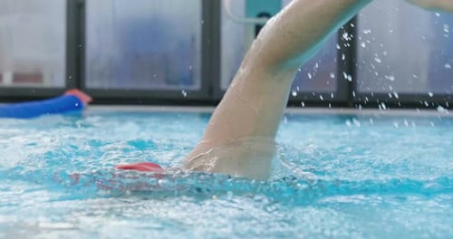 Swimmer in Pool with Red Cap Practicing Strokes