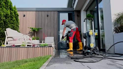 Caucasian Man Cleaning His Backyard Garden Patio Using High Pressure Washer
