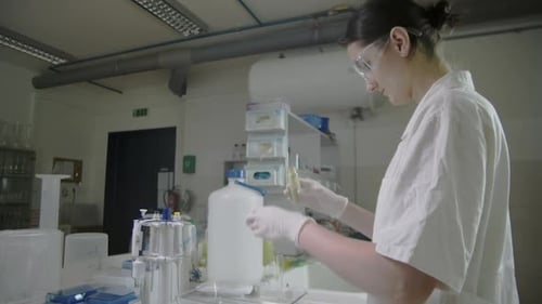 Young laboratory female scientist researching biological treatment, tilting up middle view