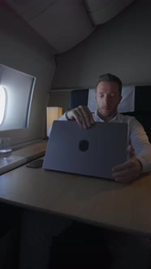 Man Using Laptop on Airplane for Business Trip