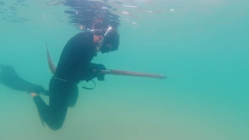 Spearfishing on the Wreck Man Swims Underwater in the Murky Sea and Reloads the Speargun