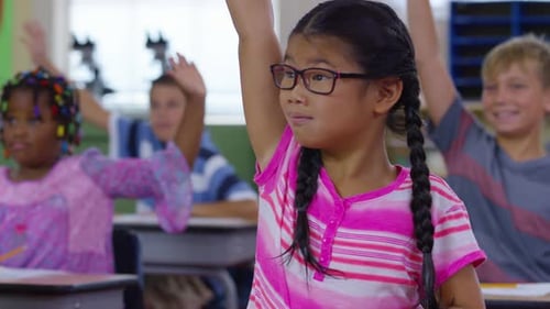 Enthusiastic students raise hands answering teacher in bright school classroom