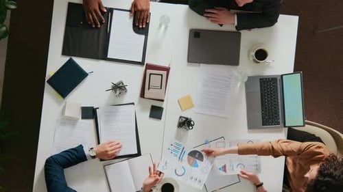 El punto de vista de una gerente femenina que entrega documentos a tres compañeros de trabajo varones