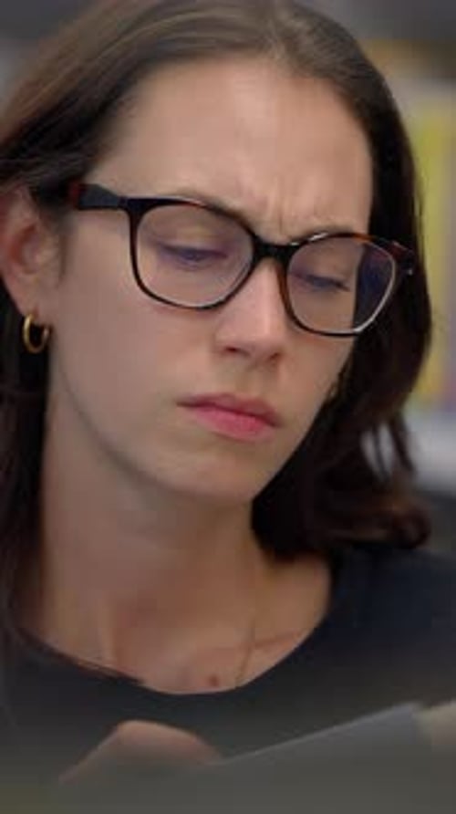Woman puts on glasses, intently reading material