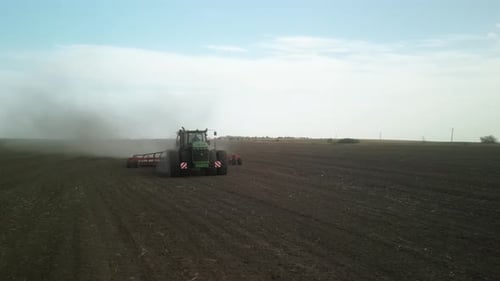 Green tractor seeding wheat on the field