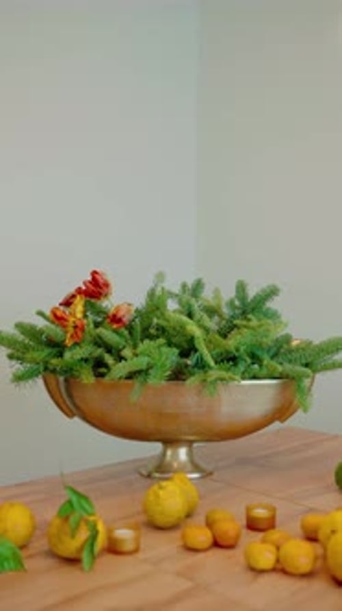 Woman Arranging Festive Winter Flower Arrangement on Table